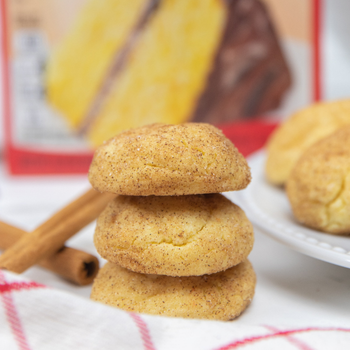 Whip up these cake mix snickerdoodles that take just 5 ingredients to make. A great beginners cookie recipe that is light and fluffy! #passion4savings #cakemix #cookies #snickerdoodles #easy #beginner #baker #holiday #cookieswap #simple cookies stacked on top of each other, with cinnamon sticks behind it