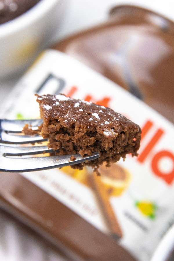 3 ingredient nutella mug cake recipe is so simple to make. Just a few ingredients is all it takes and 2 minutes to cook. A single serve treat. #passion4savings #nutella #cake #dessert #easy #homemade #mugcake #mugdessert #nutellarecipe fork with some cake above a nutella container