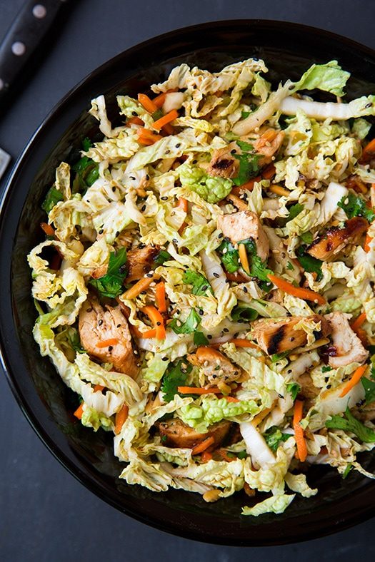 Asian grilled chicken salad on black plate on table 