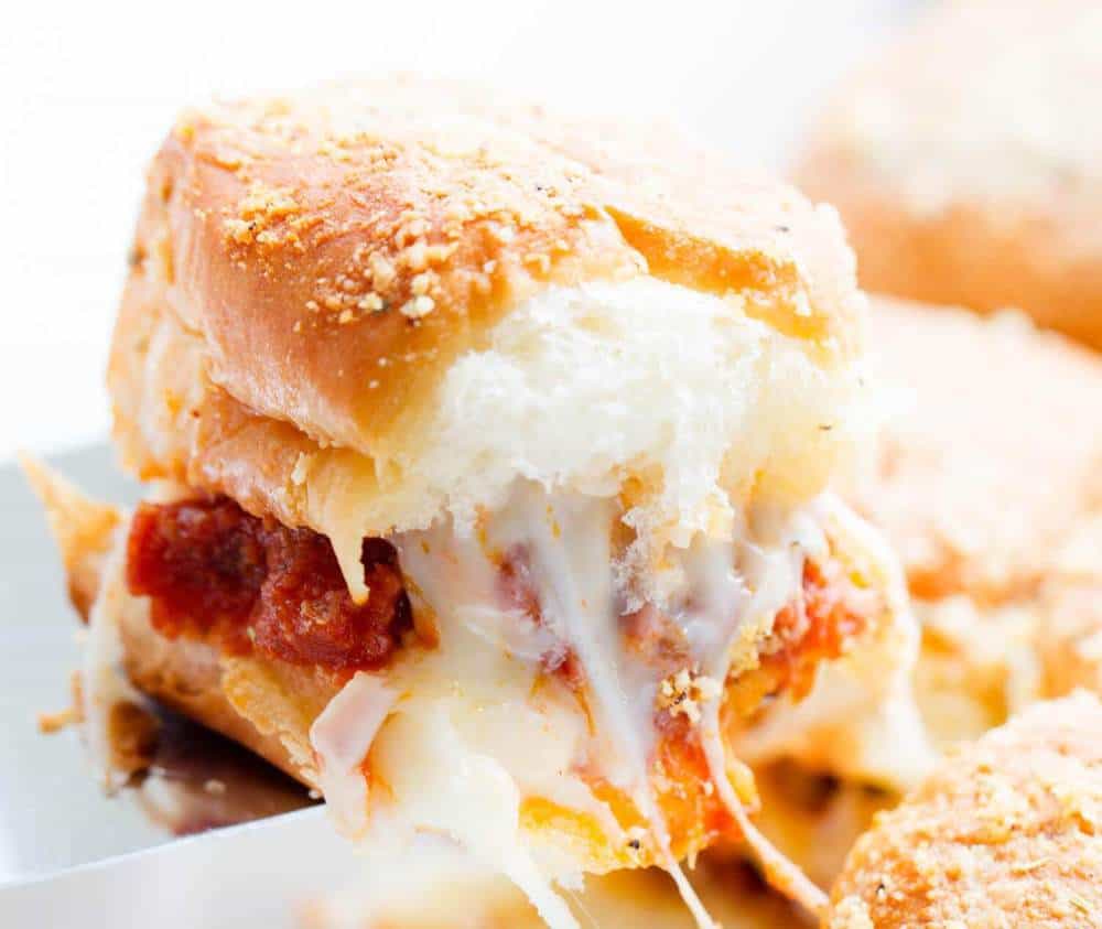 Serve up one or more of these Genius slider recipes. A simple slider bun that is filled with all your favorite fixings and baked to perfection! #passion4savings #sliders #easy #appetizer #dinner #simple #quick #nofuss cheesy meatball slider being lifted from pan