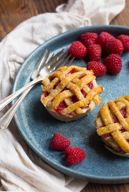 mini raspberry pies on plate iwth fresh berries around it 