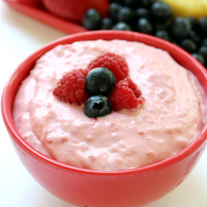 red bowl with fruit dip in it topped with berries 
