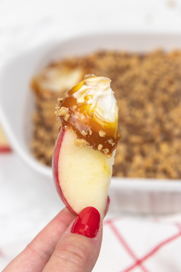 holding apple with cream cheese and caramel dip 