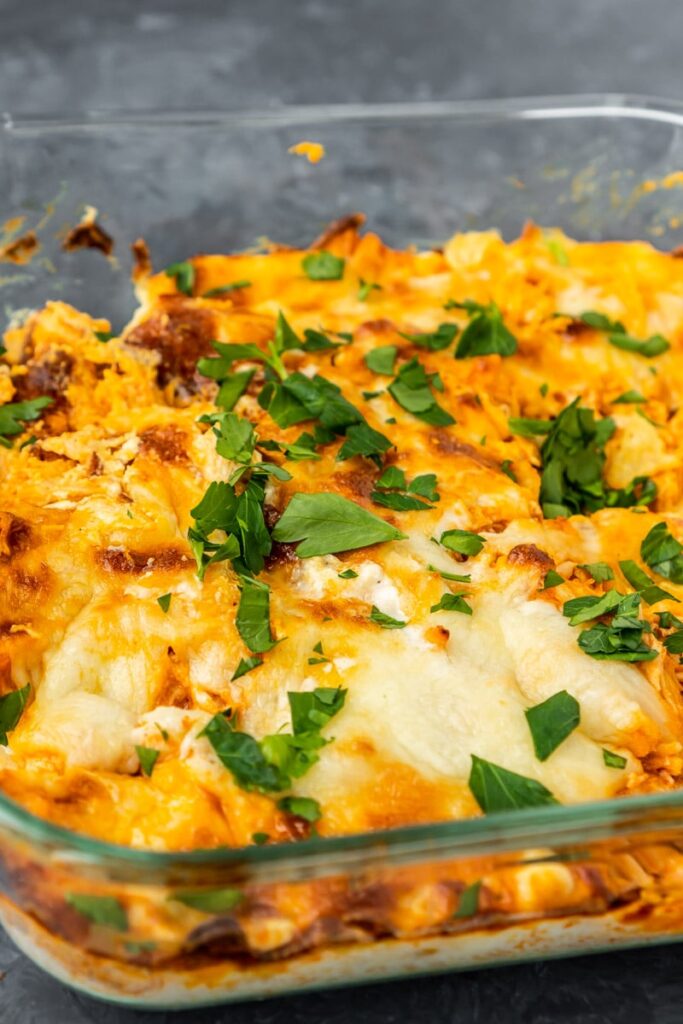 cheesy buffalo chicken in a baking dish with green garnish