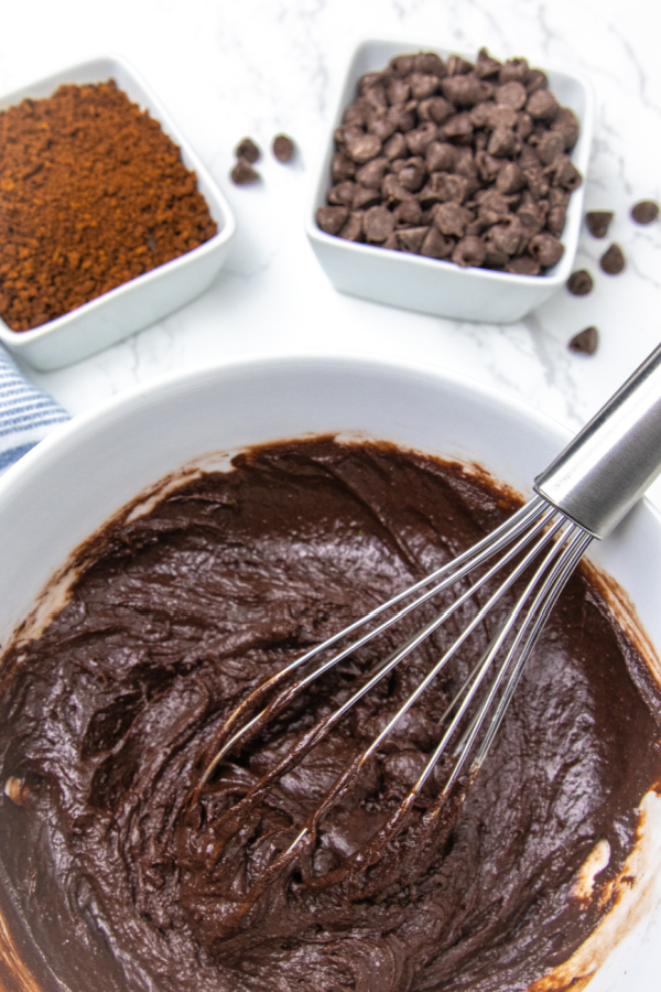 Serve up this incredible chocolate pudding cake. Layers of flavors that bake to a gooey pudding texture. A must make chocolate cake recipe. A melting cake that you will want to make over and over again. #cake #chocolate #magic #melting #pudding #rich #potluck #dessert #easy #homemade #fromscratch cake batter in bowl with whisk in it