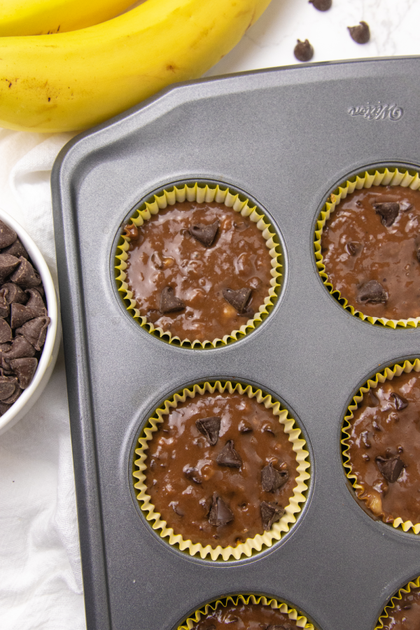 chocolate banana muffins in a muffin tin with raw dough