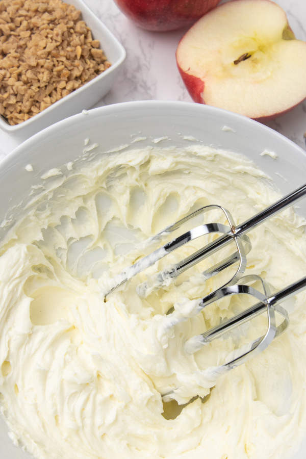 blending up cream cheese in a bowl with hand mixer 