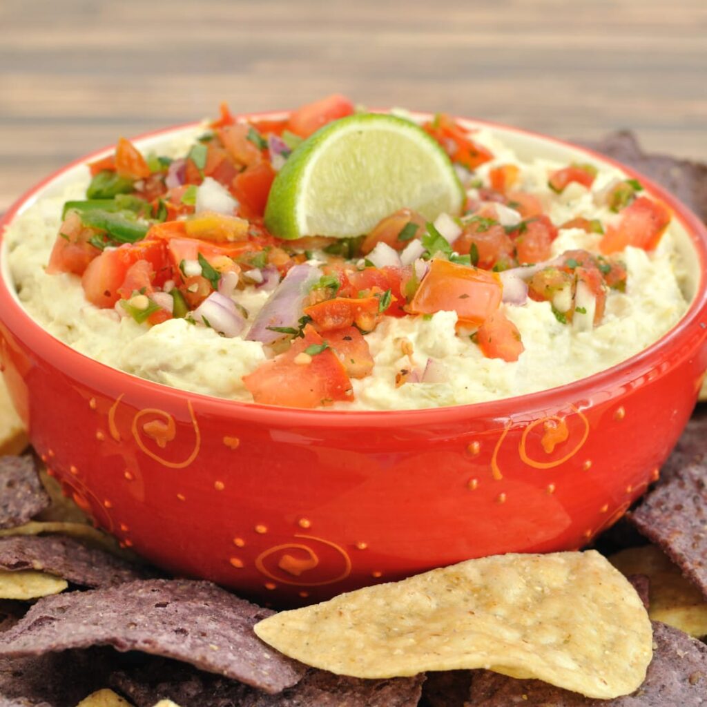 Margarita chicken dip in red bowl with chips around it 