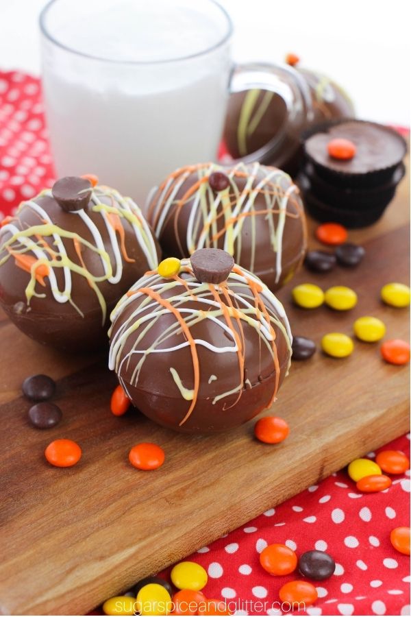 reeses pieces cocoa bombs on wooden counter with candy around them 