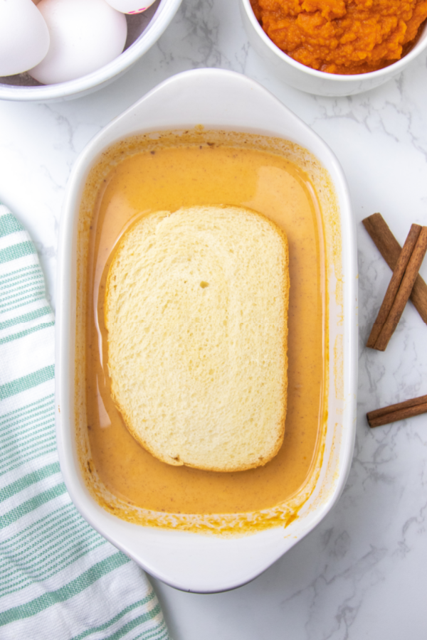 Pumpkin French Toast is going to be a game-changer for your breakfast meal. This French toast is loaded with warm cinnamon and pumpkins pie spice as well as pumpkin puree. Give this easy pumpkin spice French toast a try today! #passion4savings #pumpkin #pumpkinspice #breakfast #fall #autumn #texastoast #easy #fallflavor bread in a pumpkin batter in baking dish