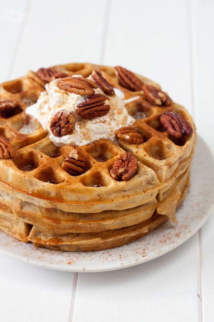 stack of waffles with butter and pecans on top 