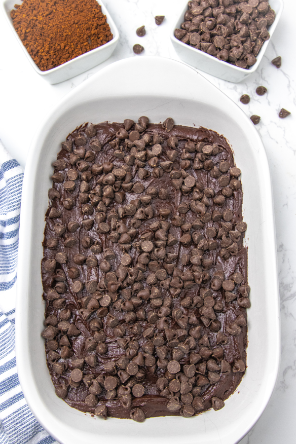 Serve up this incredible chocolate pudding cake. Layers of flavors that bake to a gooey pudding texture. A must make chocolate cake recipe. A melting cake that you will want to make over and over again. #cake #chocolate #magic #melting #pudding #rich #potluck #dessert #easy #homemade #fromscratch overhead shot of cake with chocolate chips on it