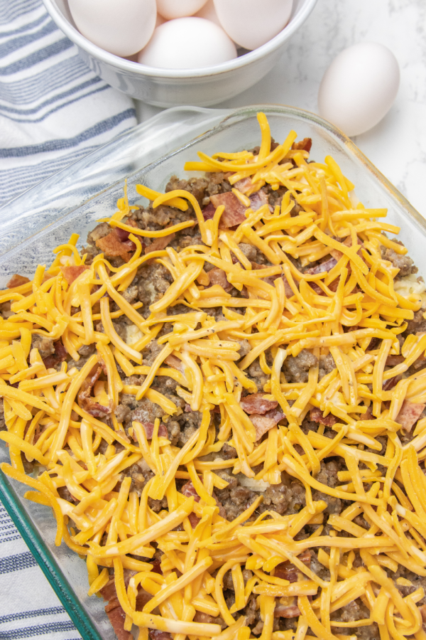 Breakfast Casserole with Hashbrowns is the perfect way to kickstart your day. Bacon, sausage, hashbrowns, all baked in one cheesy casserole. Make ahead breakfast casserole for holidays, or meal prepping breakfast! #passion4savings #breakfast #casserole #hashbrowns #bacon #sausage #cheesy #recipe #fromscratch overhead shot of sausage casserole with sprinkled cheese on top