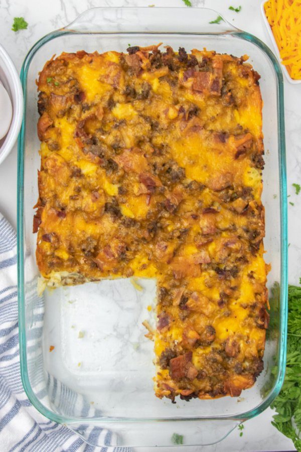 Breakfast Casserole with Hashbrowns is the perfect way to kickstart your day. Bacon, sausage, hashbrowns, all baked in one cheesy casserole. Make ahead breakfast casserole for holidays, or meal prepping breakfast! #passion4savings #breakfast #casserole #hashbrowns #bacon #sausage #cheesy #recipe #fromscratch breakfast casserole overhead shot with some cut out of pan