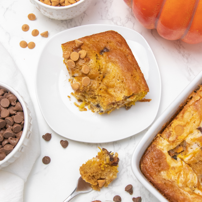 Slice and serve up this incredible pumpkin earthquake cake. A pumpkin cake filled with coconut, pecans, cream cheese swirl and much more. #passion4savings #pumpkin #cake #earthquake #cakemix #fall #dessert #easy #best #holiday #falldessert piece of pumpkin cake on table with ingredients around it