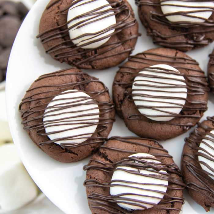 Serve up these easy hot chocolate cookies today. These are a cute and fun chocolate cookie topped with marshmallow and chocolate! Try today. #hotchocolate #cocoacookies #dessert #passion4savings #dessertidea #holiday #christmas #winter #cakemix #devilsfood hot chocolate cookies on white platter