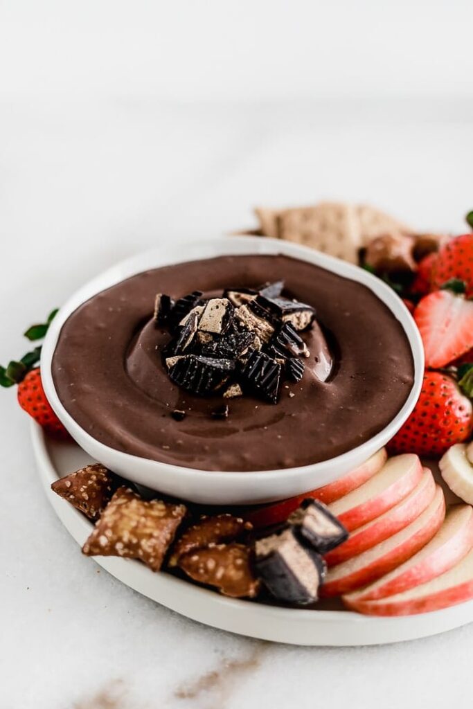peanut butter cup dip with fruit and pretzels around it 