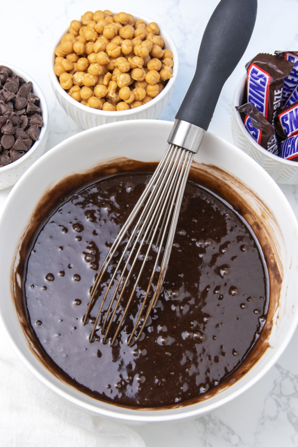 brownie batter in a bowl with whisk in it 