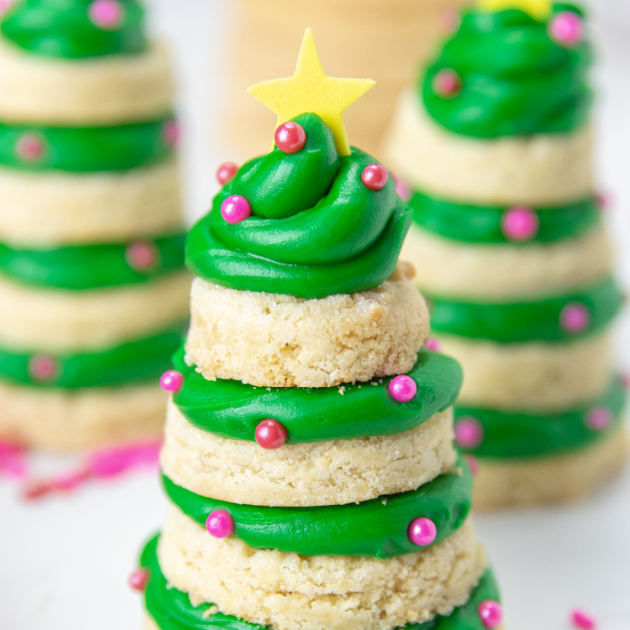 Whip up a batch of these sugar cookie Christmas Trees! These are a 3D cookie that are a stacked cookie that is festive and delicious. #passion4savings #Christmas #cookies #dessert #holiday #xmas #sugarcookie #frosting 3d sugar cookies on white counter