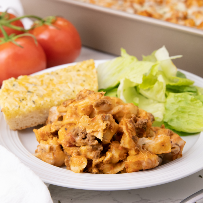 cheesy tortellini and garlic bread on plate with salad 