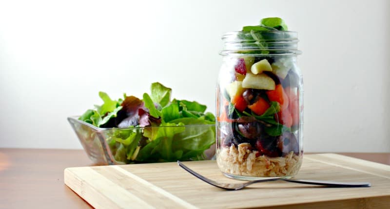 tuna salad in jar with a bowl of salad behind it 