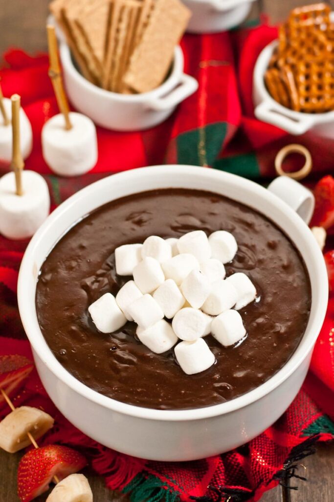 hot chocolate dip in a white bowl with marshmallows around it 