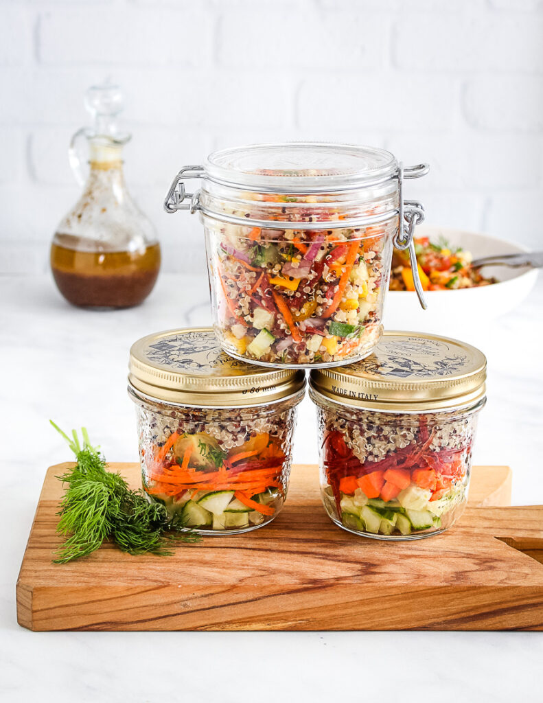 stacked quinoa filled mason jars on wooden cutting board 
