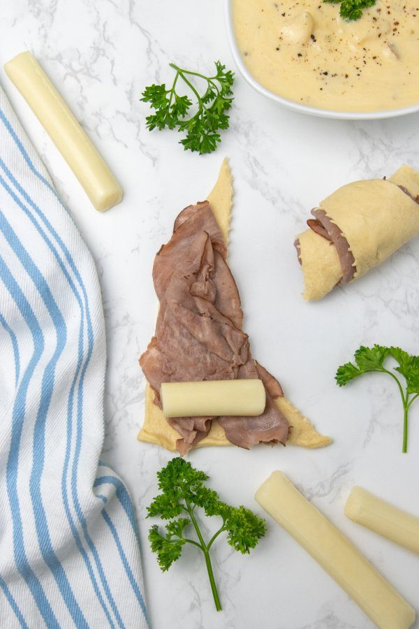 crescent roll with roast beef and cheese on it on marble counter 