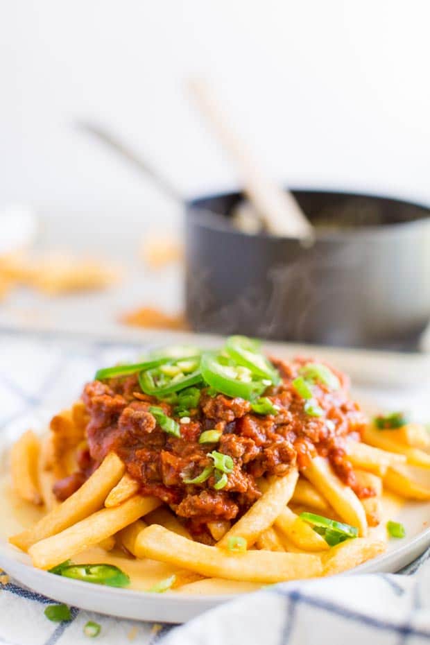chili cheese fries piled on plate with pan behind it 