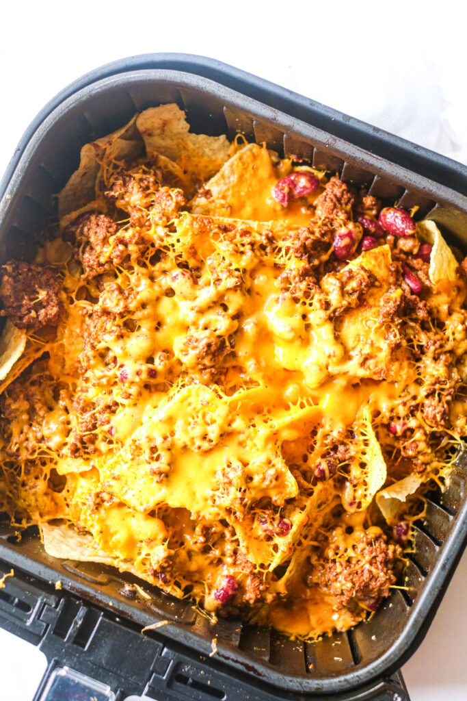 air fryer with chili cheese nachos in side with melted cheese 