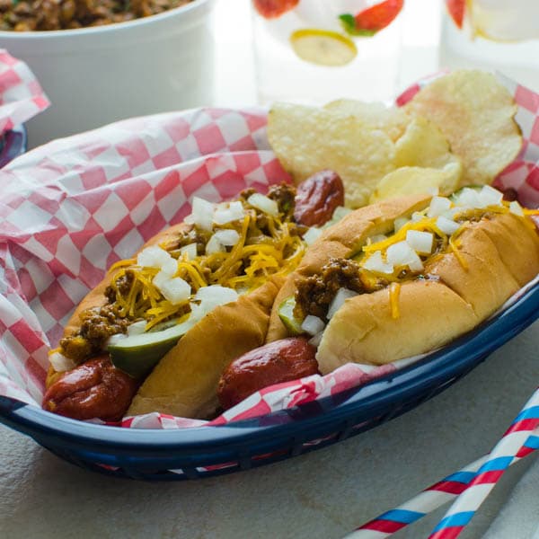 chili cheese dogs in a basket with chips on side 
