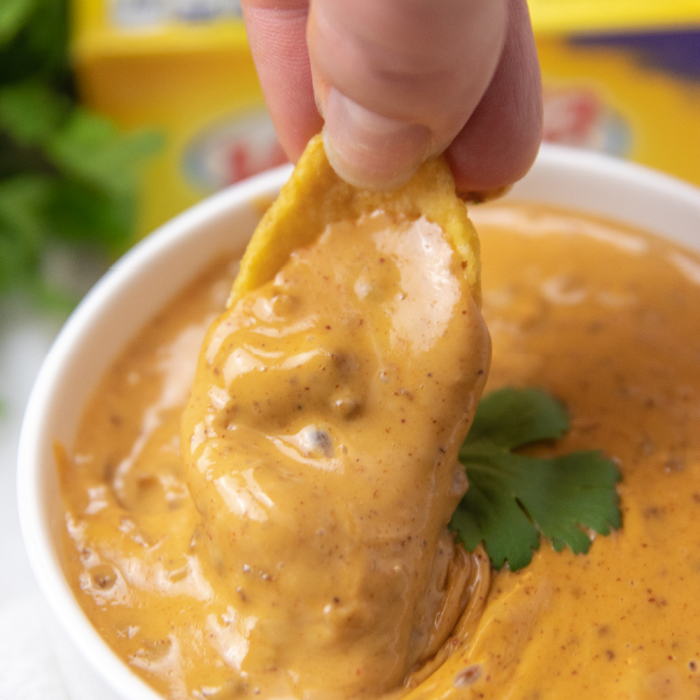 Frito chip dipping into chili cheese dip 
