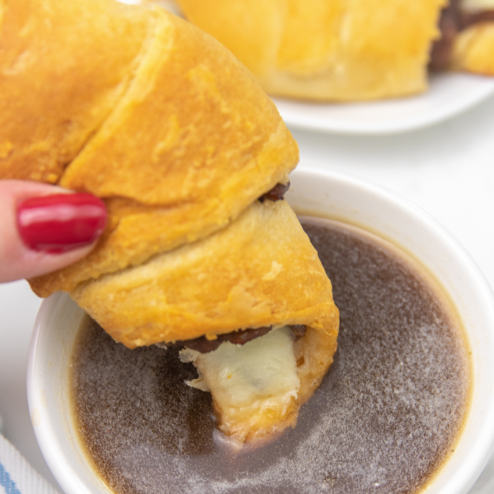 French Dip Crescent Rolls are a simple and easy dinner or appetizer to serve up. Buttery crescent rolls, string cheese and deli cut roast beef. A simple and satisfying dish with a side of au jus for dipping. #crescentrolls #passion4savings #roastbeef #crescentrecipe #easy #quick #dinner #recipe #aujus roast beef sandwich dipped in au jus