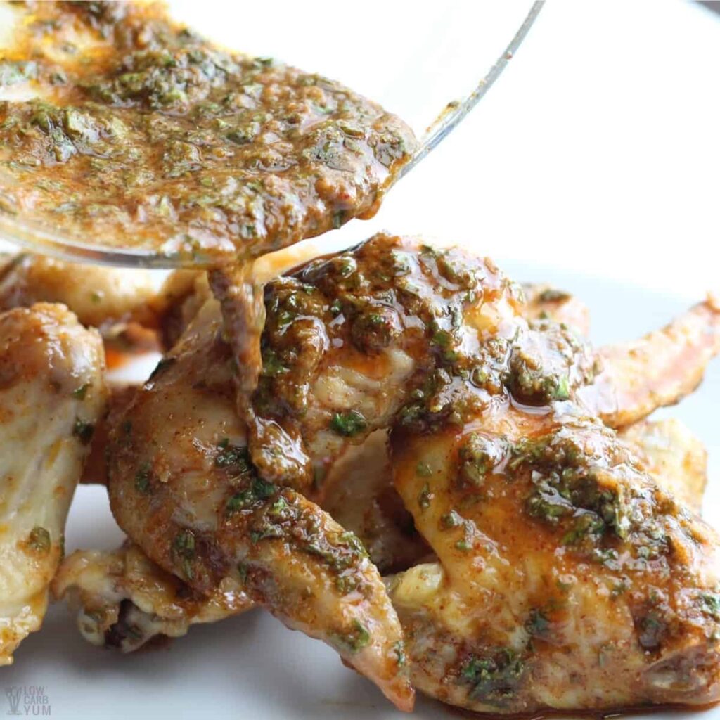 pouring sauce over wings on counter 