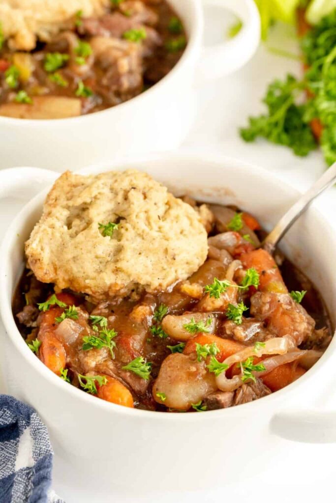beef stew with dumplings in a bowl with biscuit on top 