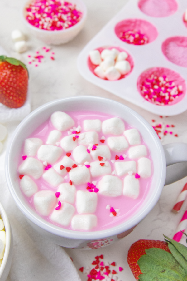 pink hot chocolate in mug with sprinkles on top 