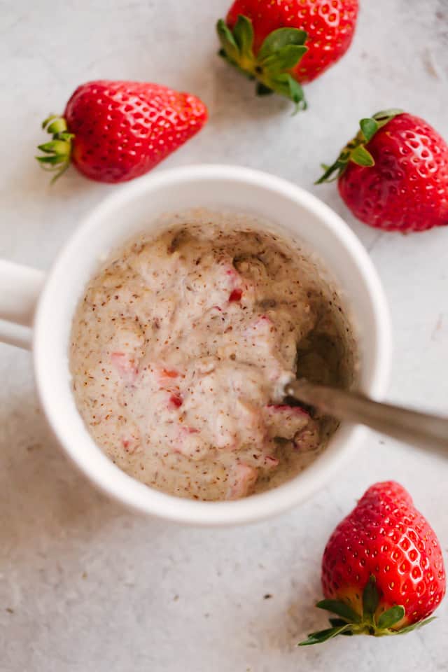 strawberry mug cake with berries around it 