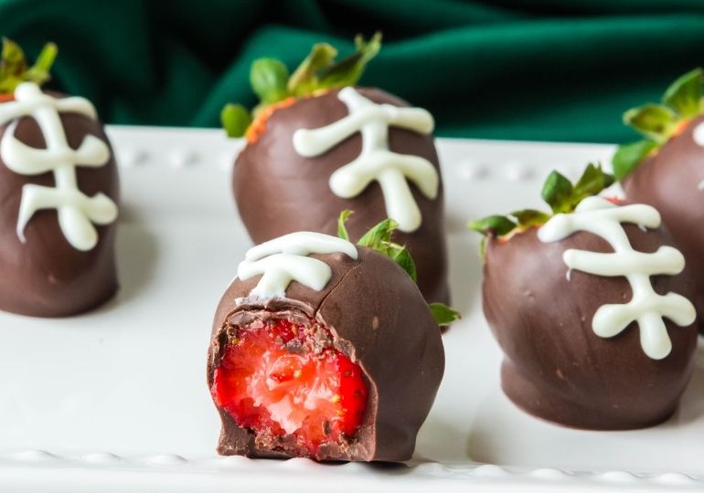 chocolate covered strawberries decorated like footballs on table 