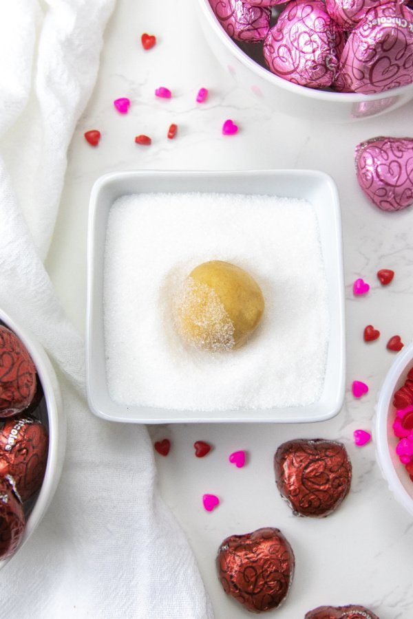 peanut butter cookie dough in bowl of sugar on table 