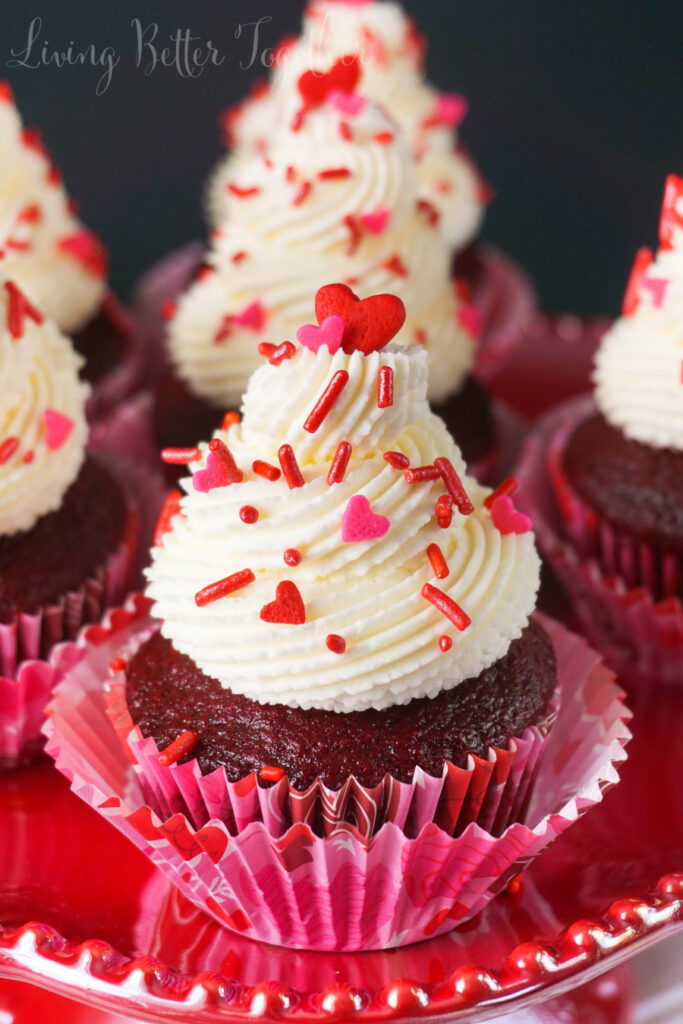 red velvet cupcakes on table topped with frosting 