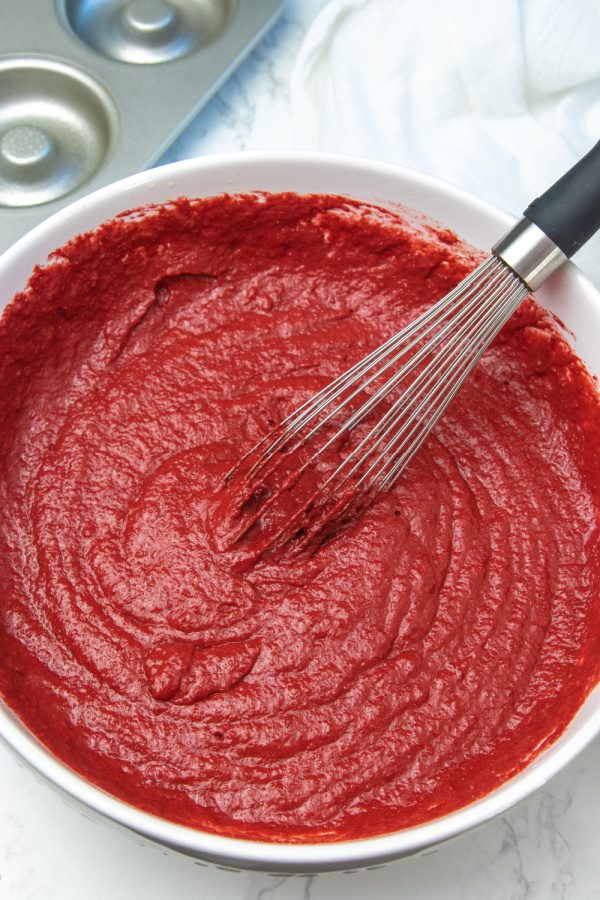 red velvet donut mixture in a bowl with whisk
