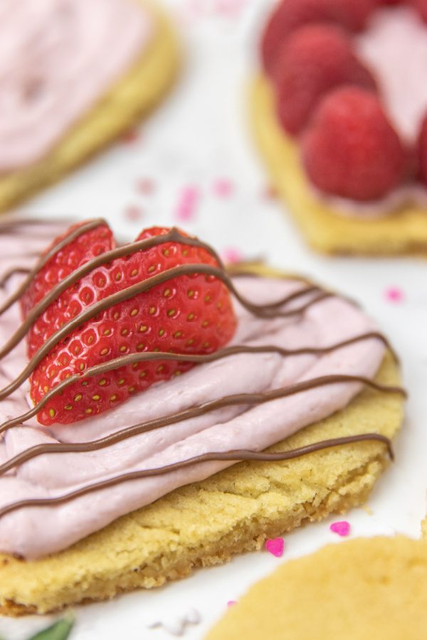 Whip up these quick and easy Mini Valentine Dessert Pizzas. A sugar cookie pizza dessert to serve up this Valentine's Day. #valentinesday #dessert #pizza #holiday #passion4savings #easy #quick #sugarcookie #cookiedough valentine dessert pizzas