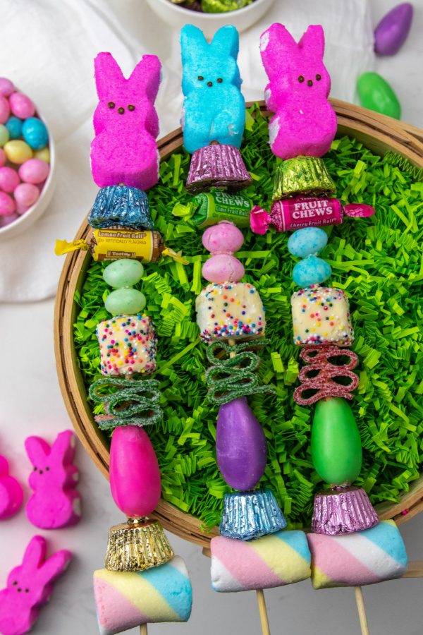 Peeps candy kebabs are a cute and fun Easter treat to make for your Easter celebration. Bright colored candies on skewers. #passion4savings #easy #peeps #candy #kebabs #holiday #kidfriendly #forkids skewers candy kebabs on top of an easter basket