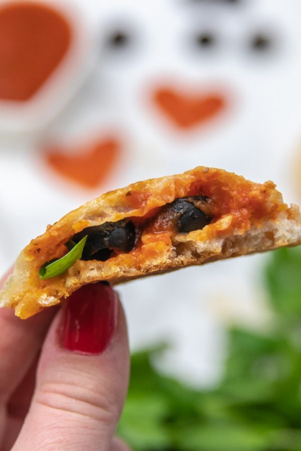 pizza calzones in hand bitten in half 