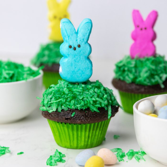 Peeps Easter Bunny Cupcakes are a chocolate cupcake with coconut and a marshmallow frosting. Top it off with a Peep, perfect for Easter! #passion4savings #peeps #easter #cupcakes #dessert #marshmallow #easy #cute #festive #fun #holidaydessert cupcakes on table with peeps on top