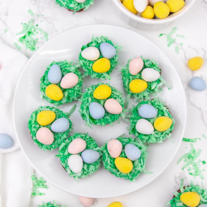 Easter nest brownie bites are a mini brownie topped with a marshmallow frosting, colored coconut and candy eggs. An easy Easter treat! #passion4savings #easter #dessert #bitesize #holiday #birdnest #kidfriendly #best brownies on a plate that look like bird nests