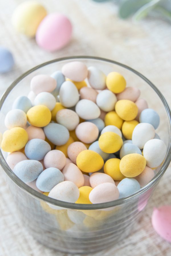 This Easter Candy Centerpiece takes 5 minutes to make. A simple and elegant Easter centerpiece that uses candy and faux flowers. Learn how to dress up your home in minutes for Easter. #passion4savings #easter #centerpiece #easy #quick #fauxflowers #flowers #candy easter candy in a glass vase