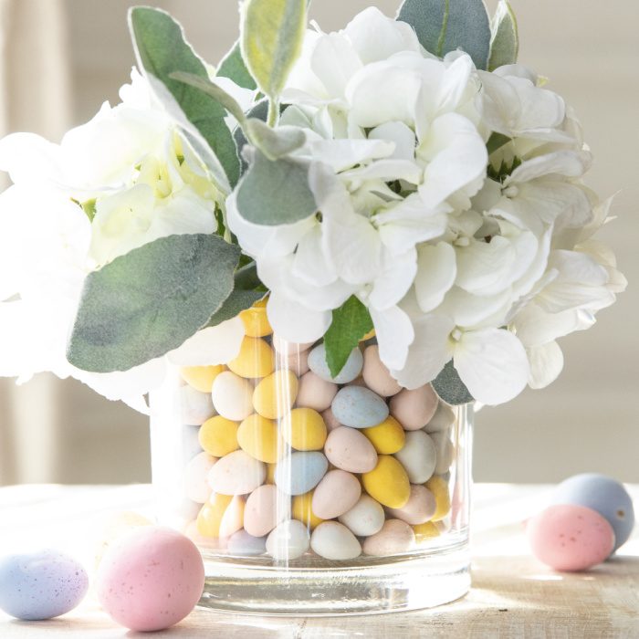 This Easter Candy Centerpiece takes 5 minutes to make. A simple and elegant Easter centerpiece that uses candy and faux flowers. Learn how to dress up your home in minutes for Easter. #passion4savings #easter #centerpiece #easy #quick #fauxflowers #flowers #candy candy filled Easter flower centerpiece