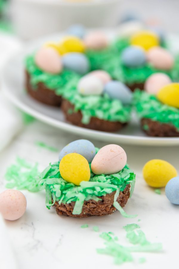 Easter nest brownie bites are a mini brownie topped with a marshmallow frosting, colored coconut and candy eggs. An easy Easter treat! #passion4savings #easter #dessert #bitesize #holiday #birdnest #kidfriendly #best frosted brownies