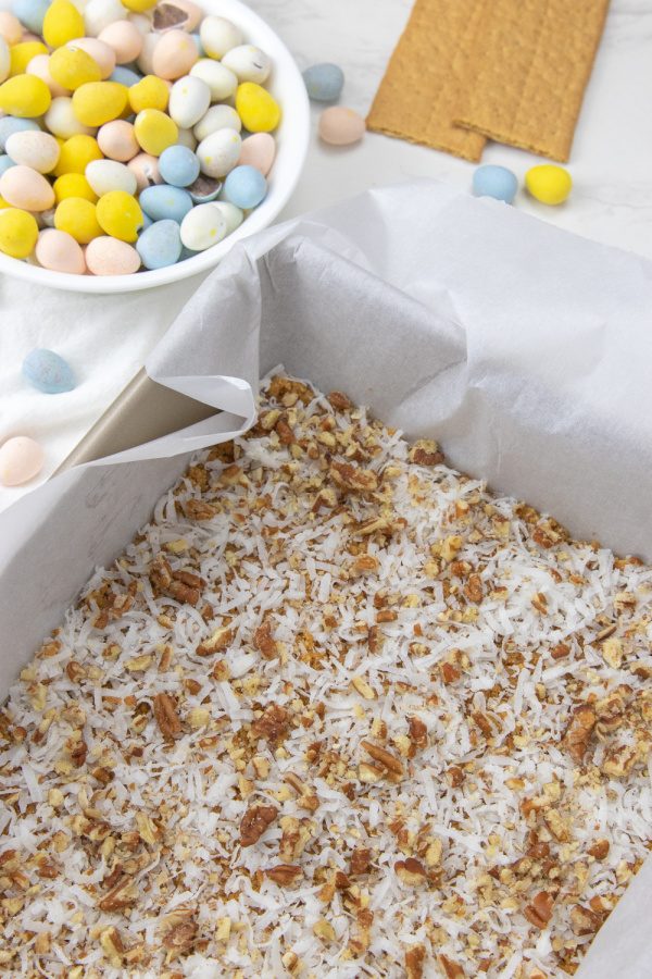 coconut and pecans sprinkled in pan with cadbury eggs in bowl 